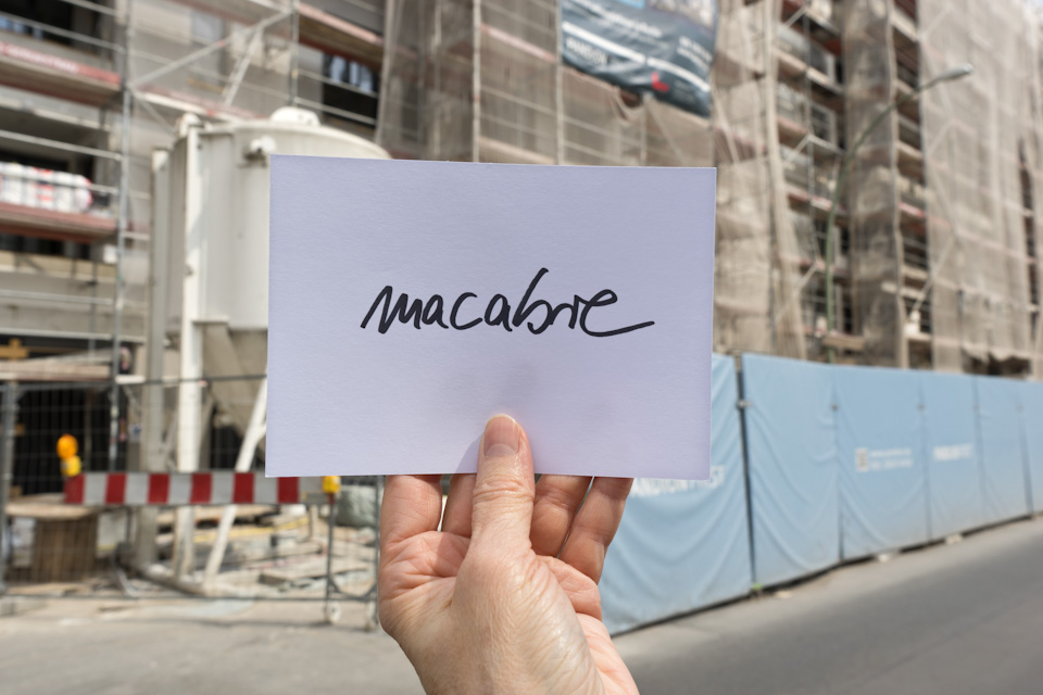 evaluation card "macabre" in front of construction site fence